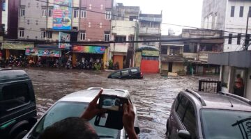 Warga mengabadikan mobil yang terseret banjir akibat hujan deras, di Jalan Pagarsih, Kota Bandung, Senin (24/10/2015). Selain cuaca buruk, diperparah dengan kondisi drainase yang tidak bisa menampung limpasan air yang mengalir. foto : BNPB